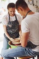 con sua fidanzato o marito. giovane femmina ceramista in casa con fatto a mano argilla Prodotto. concezione di ceramica foto