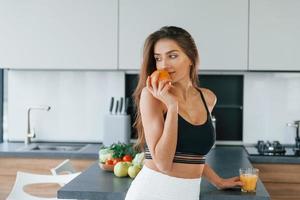 fresco arancia. giovane europeo donna è in casa a cucina in casa con salutare cibo foto