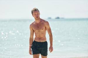 chiaro acqua. giovane europeo uomo avere vacanza e godendo gratuito tempo su il spiaggia di mare foto