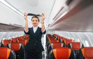 sicurezza Istruzioni. giovane hostess su il opera nel il passanger aereo foto