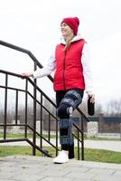 donna indossare ginocchio sostegno o ortesi dopo gamba chirurgia, a piedi nel il parco foto