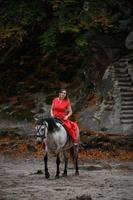 colomba rocce e cavallo cavalcare, un' donna equitazione un' cavallo nel un' rosso vestito con spoglio piedi. foto