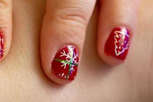 un' avvicinamento di rosso chiodo manicure design con fiocco di neve foto