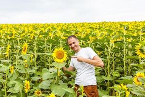 riuscito ucraino contadino nel un' girasole campo. contadino uomo è in piedi e sorridente nel un' campo con un' tranquillo, calmo cielo sfondo. Ucraina. agricoltura e seme olio produzione. foto