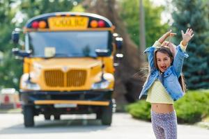 poco ragazza con zaino va per scuola autobus foto