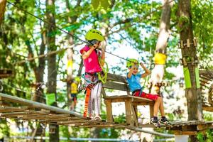 contento poco bambini nel un' corda parco su il legna sfondo foto