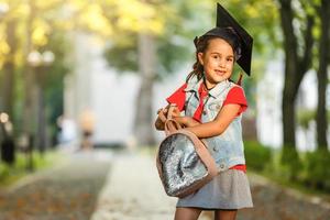 bellissimo attraente diplomato nel berretto e toga Sorridi Tenere libro e certificato nel avvio giorno sensazione così orgoglioso e felicità, educazione successo concetto foto