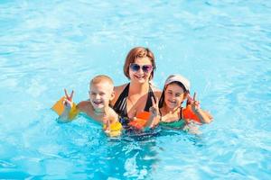 bellissimo giovane madre con poco figlio e figlia nel piscina. foto