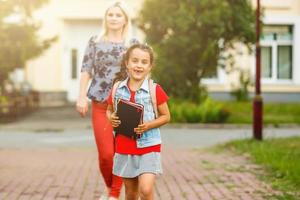 giovane madre conduce sua figlia per scuola. foto