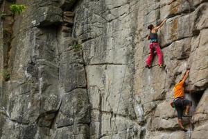 un' giovane donna con un' corda impegnato nel il gli sport di roccia arrampicata foto