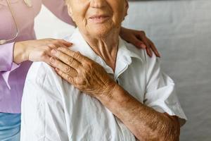 anziano femmina mano Tenere mano di giovane badante a assistenza infermieristica domiciliare.geriatrico medico o geriatra concetto. medico medico mano su contento anziano anziano paziente per comfort nel ospedale visita medica foto