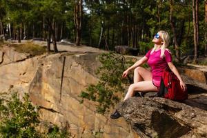 escursionista con zaino rilassante su un' roccia e godendo tramonto foto