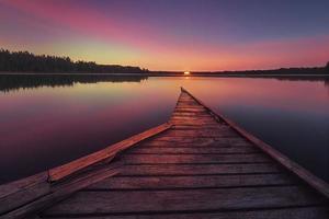 colorfull di legno molo su un' lago quello è totalmente calma durante tramonto foto
