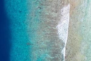 aereo mare Visualizza, superiore Visualizza di sorprendente natura oceano sfondo. luminosa blu acqua colori, laguna spiaggia con onde spruzzi a soleggiato giorno. volante fuco foto, sorprendente natura paesaggio con corallo scogliera foto