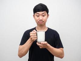 giovane uomo guardare a bicchieri di latte sentire affamato, amico gesto bastone su lingua foto