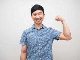 giovane uomo blu camicia mostrando muscolo contento Sorridi bene sano foto