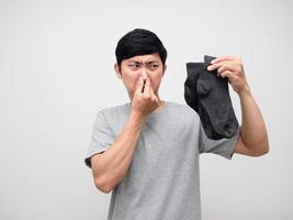 asiatico uomo Tenere sporco calzini vicino il suo naso si sente puzzolente ritratto foto