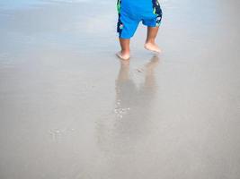 ragazzo a piedi su il sabbia sabbia della spiaggia ragazzo orma foto