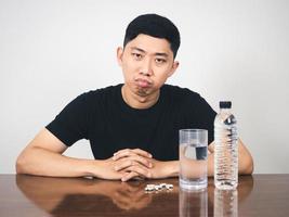 asiatico uomo si sente annoiato con medicina pillola su il tavolo foto