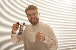 giovane uomo scrosciante caffè a partire dal moka pentola a mattina. prima colazione e rompere concetto. foto