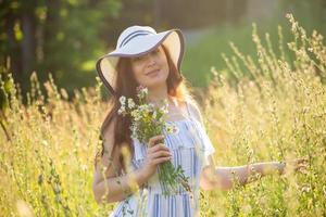 giovane donna raccolta fiori nel il prato nel estate sera foto