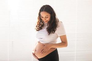 sorridente giovane bellissimo incinta donna toccante sua pancia e gioire. concetto di positivo e piacevole sentimenti mentre in attesa per il bambino. copia spazio foto