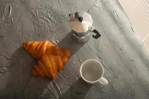 prima colazione con brioche e tazza e moka pentola. mattina pasto e prima colazione concetto. foto