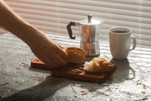 prima colazione con brioche su taglio tavola e nero caffè. mattina pasto e prima colazione concetto. foto