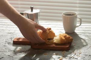 prima colazione con brioche su taglio tavola e nero caffè. mattina pasto e prima colazione concetto. foto