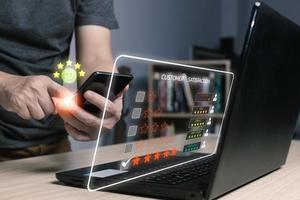 vicino su uomo mano utilizzando computer taccuino e smartphone con apparire cinque stella icona per risposta revisione soddisfazione servizio, cliente servizio Esperienza e attività commerciale soddisfazione indagine. foto