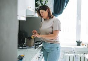 bellissimo brunetta giovane donna più dimensione corpo positivo cucinando pasta nel cucina a casa foto