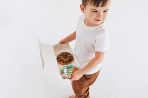 divertente carino bambino piccolo ragazzo con scatola di ciambelle su rg bianca sfondo, studio tiro foto