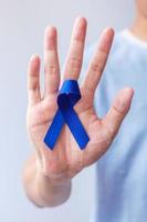 marzo mese di sensibilizzazione sul cancro colorettale, donna che tiene un nastro blu scuro per sostenere le persone che vivono e le malattie. concetto di assistenza sanitaria, speranza e giornata mondiale del cancro foto