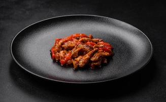 delizioso succoso carne con caldo peperoni e salsa su un' nero ceramica piatto foto