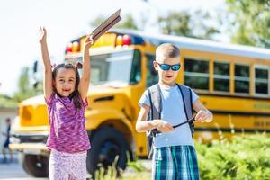 ridendo sorridente caucasico ragazzo alunno ragazzo con divertente viso espressione a piedi vicino giallo autobus su 1 settembre giorno. formazione scolastica e indietro per scuola concetto. bambino allievo pronto per imparare e studia. foto