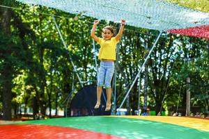 poco bambino salto su grande trampolino - all'aperto nel Giardino dietro la casa foto