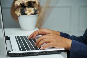 immagine di un asiatico attività commerciale uomo mani Lavorando nel ufficio con il computer portatile computer, digitando su tastiera a il suo scrivania, vicino su foto