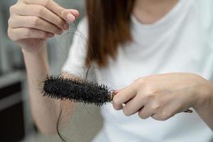 la donna asiatica ha problemi con la caduta dei capelli lunghi attaccata alla spazzola del pettine. foto