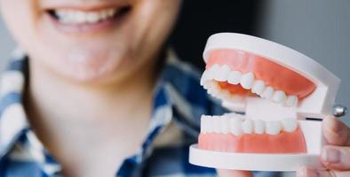 stomatologia concetto, parziale ritratto di ragazza con forte bianca denti guardare a telecamera e sorridente, dita vicino viso. avvicinamento di giovane donna a dal dentista, studio, in casa foto