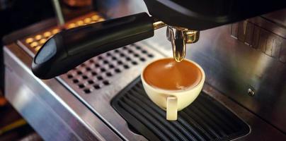 caffè tazza di caffè espresso scrosciante a partire dal il caffè macchina. professionale caffè birra nel il bar foto