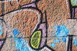 frammento di graffiti disegni. il vecchio parete decorato con dipingere macchie nel il stile di strada arte cultura. colorato sfondo struttura nel caldo toni foto