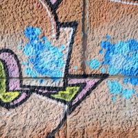 frammento di graffiti disegni. il vecchio parete decorato con dipingere macchie nel il stile di strada arte cultura. colorato sfondo struttura nel caldo toni foto