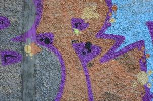 frammento di graffiti disegni. il vecchio parete decorato con dipingere macchie nel il stile di strada arte cultura. colorato sfondo struttura nel caldo toni foto