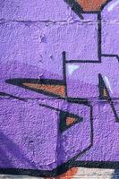 frammento di graffiti disegni. il vecchio parete decorato con dipingere macchie nel il stile di strada arte cultura. colorato sfondo struttura nel viola toni foto