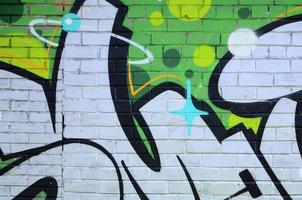 frammento di graffiti disegni. il vecchio parete decorato con dipingere macchie nel il stile di strada arte cultura. colorato sfondo struttura nel verde toni foto