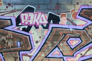 frammento di graffiti disegni. il vecchio parete decorato con dipingere macchie nel il stile di strada arte cultura. colorato sfondo struttura nel caldo toni foto