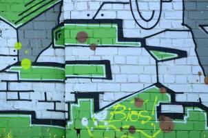 frammento di graffiti disegni. il vecchio parete decorato con dipingere macchie nel il stile di strada arte cultura. colorato sfondo struttura nel verde toni foto