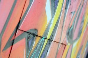 frammento di graffiti disegni. il vecchio parete decorato con dipingere macchie nel il stile di strada arte cultura. colorato sfondo struttura nel caldo toni foto