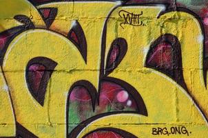 frammento di graffiti disegni. il vecchio parete decorato con dipingere macchie nel il stile di strada arte cultura. colorato sfondo struttura nel caldo toni foto