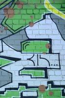 frammento di graffiti disegni. il vecchio parete decorato con dipingere macchie nel il stile di strada arte cultura. colorato sfondo struttura nel verde toni foto